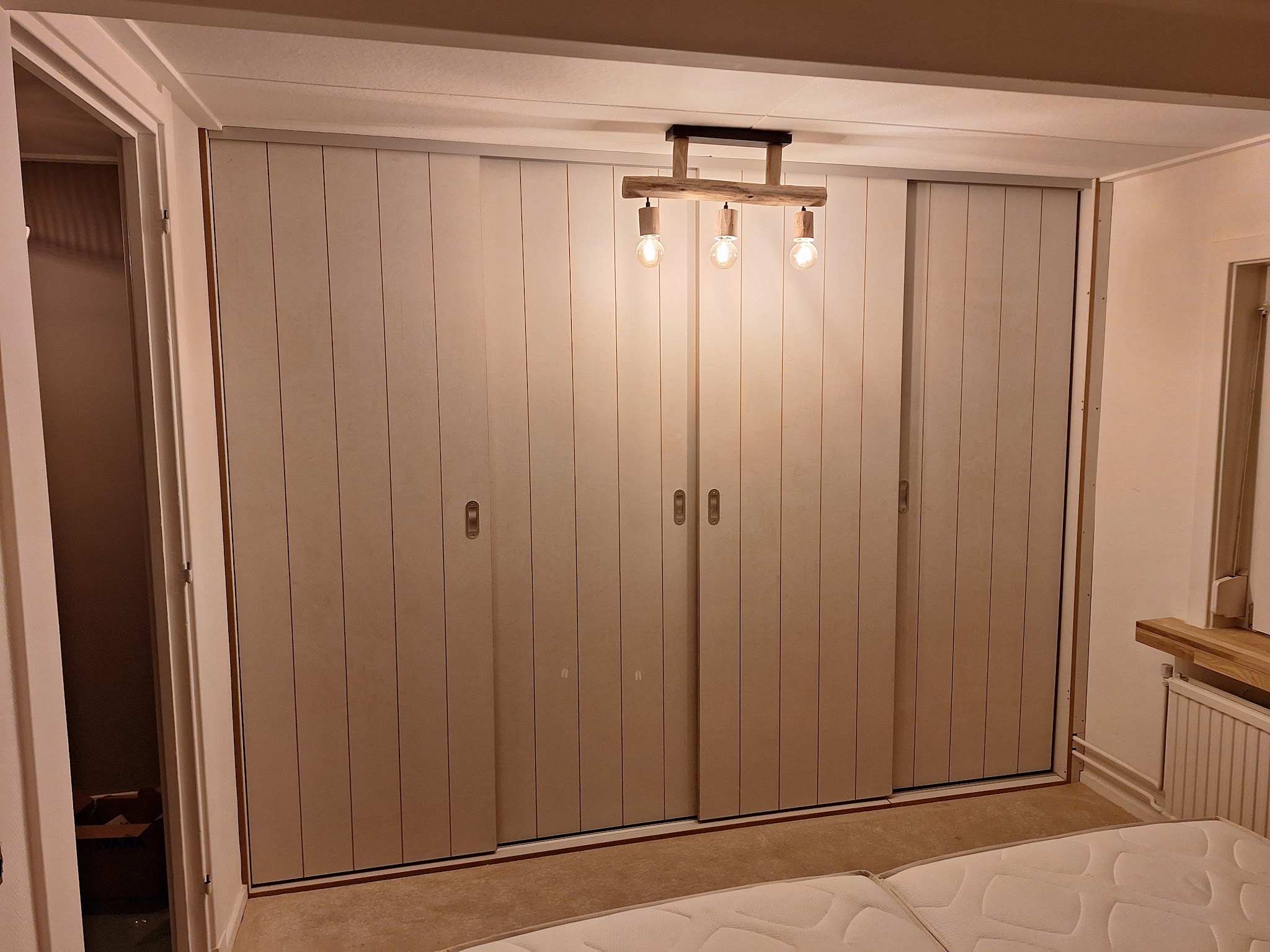 Slaapkamer met een kastenwand met verticale latten en schuifdeuren